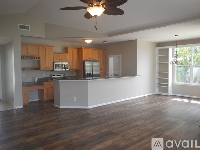 A spacious kitchen with wooden floors and a ceiling fan.