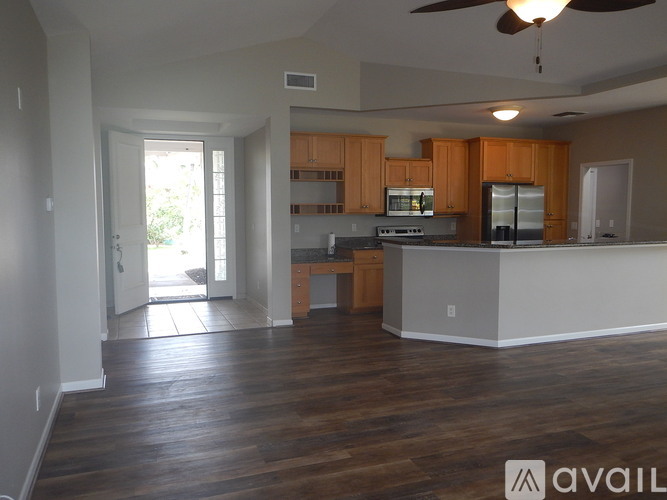 A spacious kitchen and living room with wooden floors and a ceiling fan.