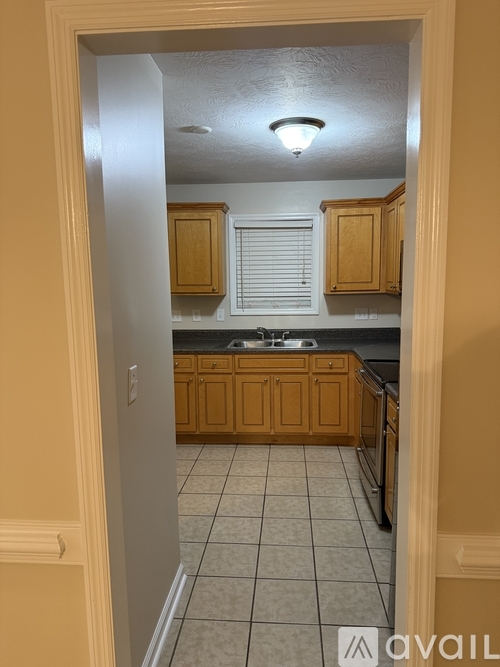A kitchen with wooden cabinets and a tiled floor.