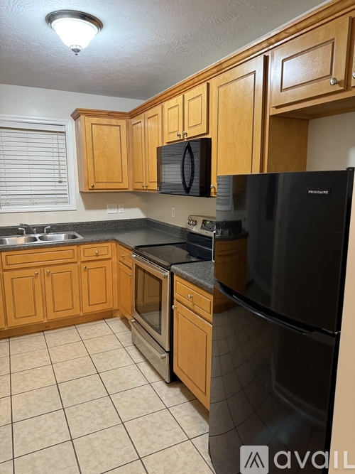 A kitchen with wooden cabinets and a black fridge.