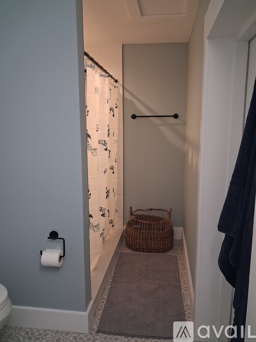 A bathroom with a toilet, a basket, and a towel rack.