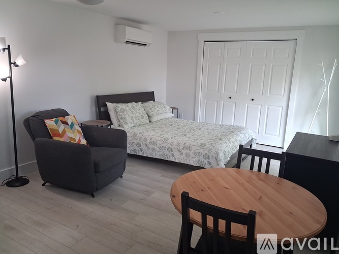 A bedroom with a bed, a chair, and a table.