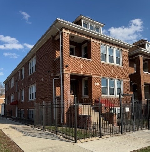 A red brick building with a black fence in front.