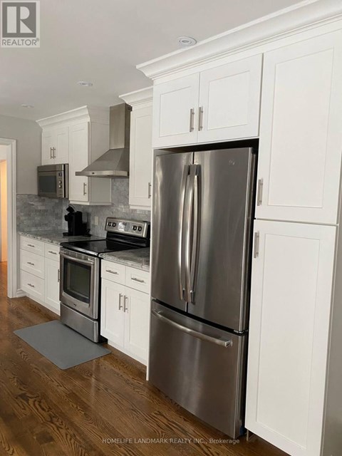 A modern kitchen with a stainless steel refrigerator and white cabinets.