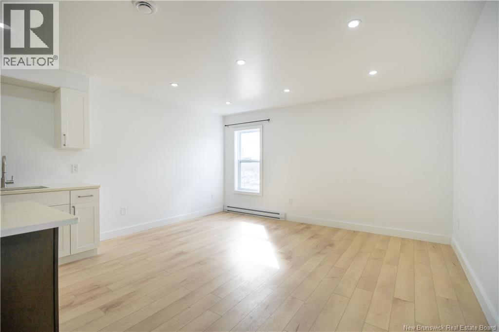 A large empty room with wooden floors and a window.