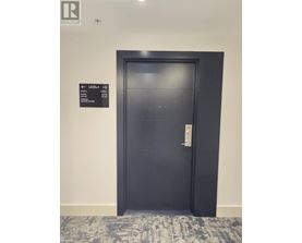 A black door with a sign on the wall above it.