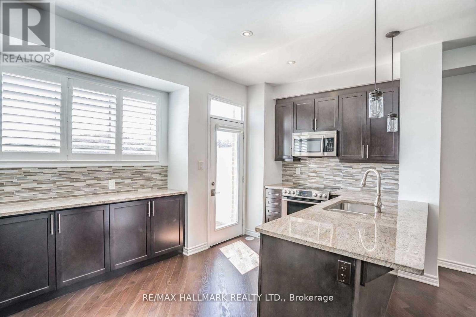 A kitchen with dark wood cabinets and a granite countertop.