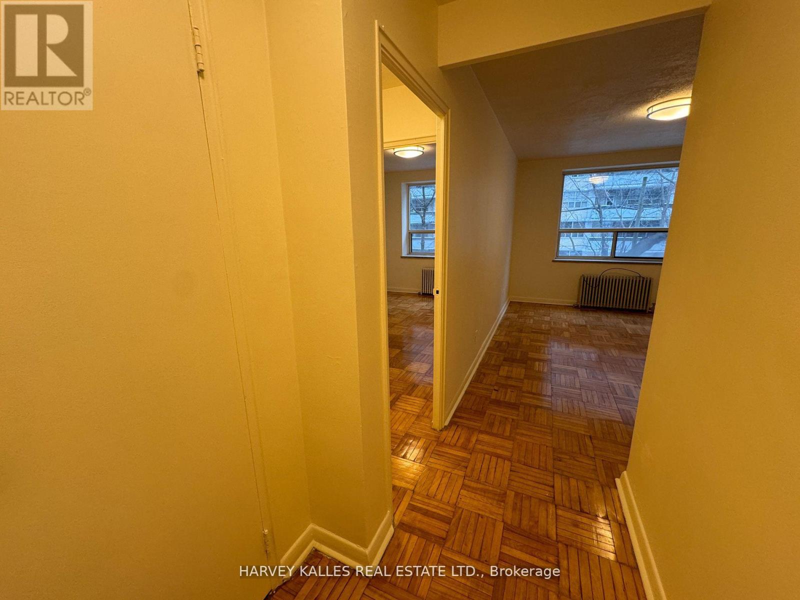 A hallway with a wooden floor and a window in the distance.