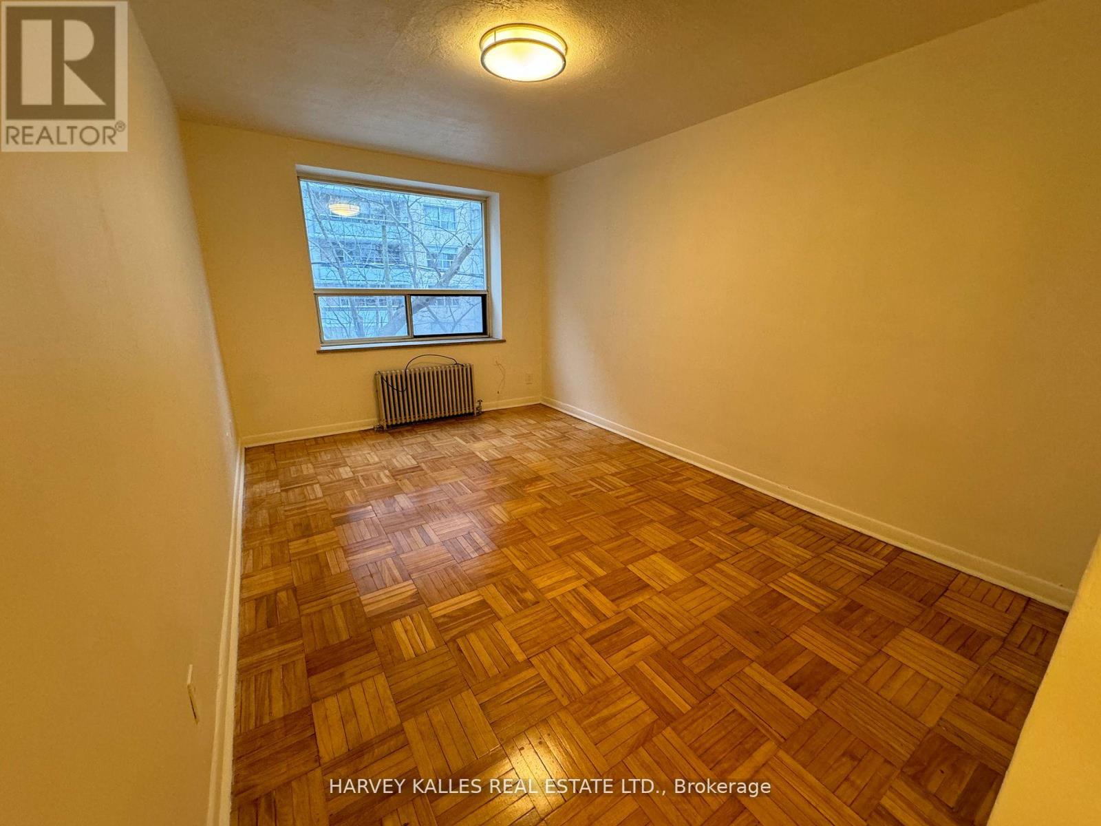 A room with wooden flooring and a window with a view of a building outside.