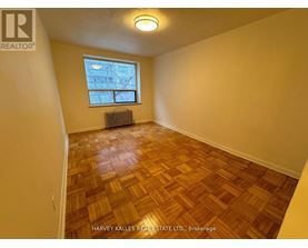 A room with wooden flooring and a window with a view of a building outside.
