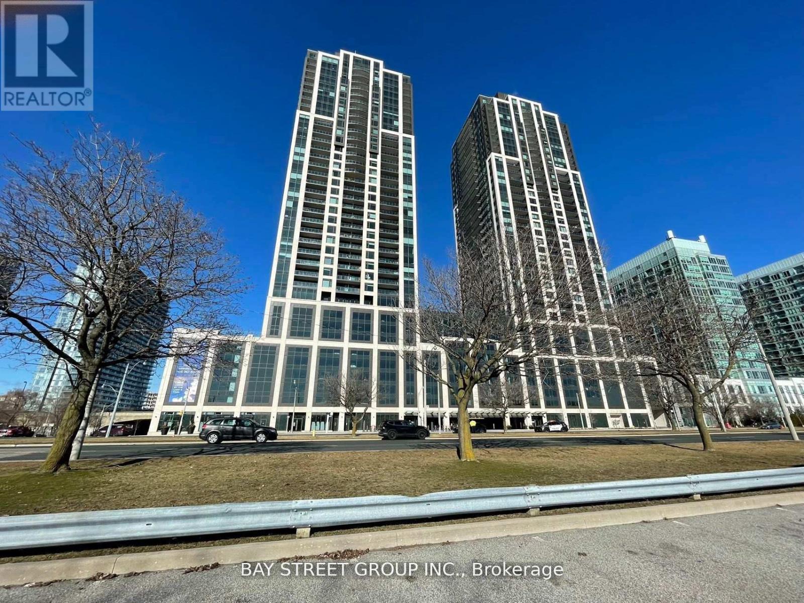 Two tall buildings are in the foreground with a car parked in front of them.