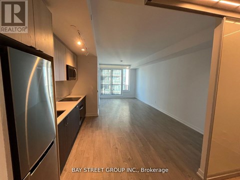 A kitchen with a refrigerator and wooden floors.