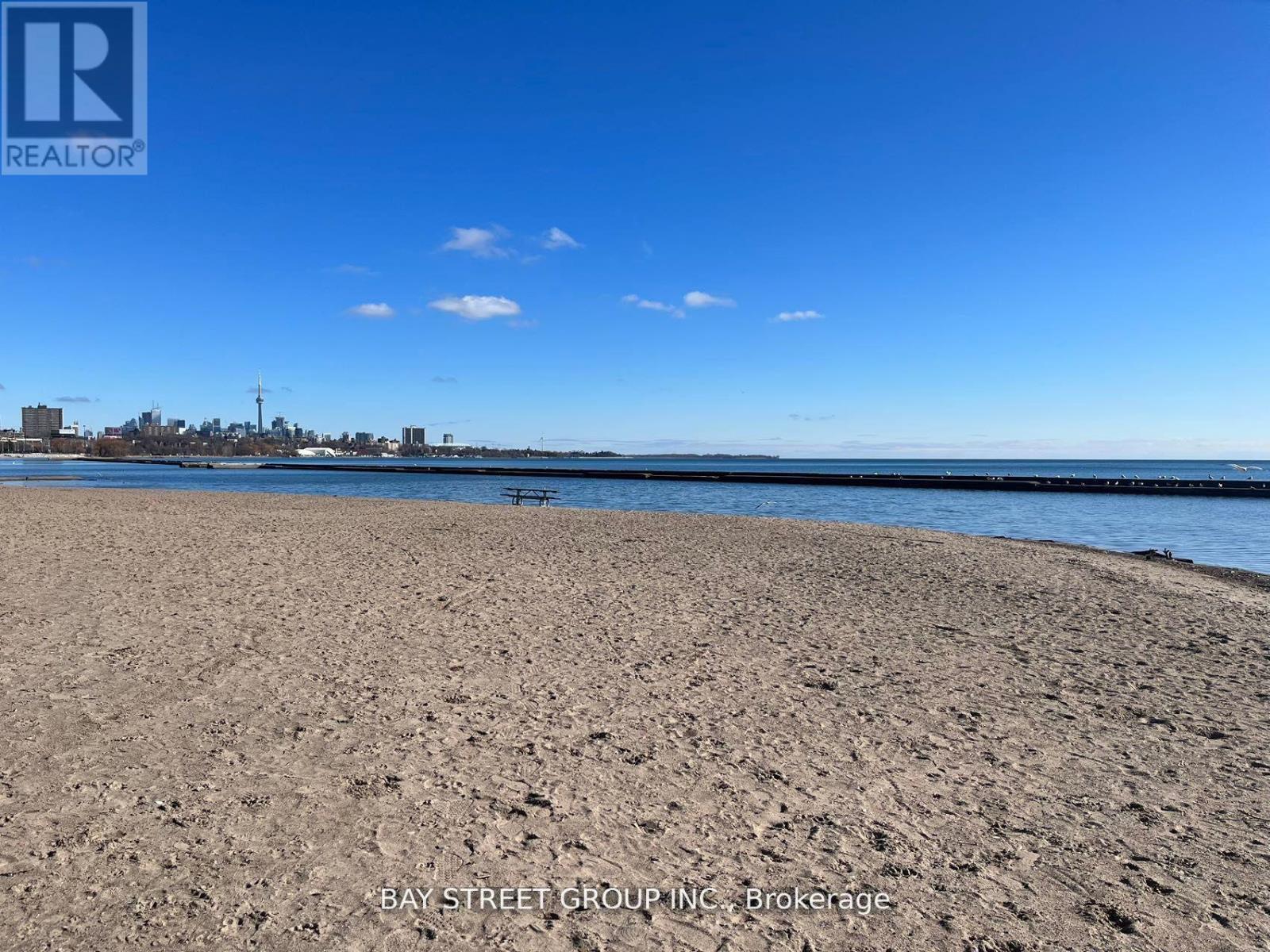 A beach with a clear blue sky and a few clouds.