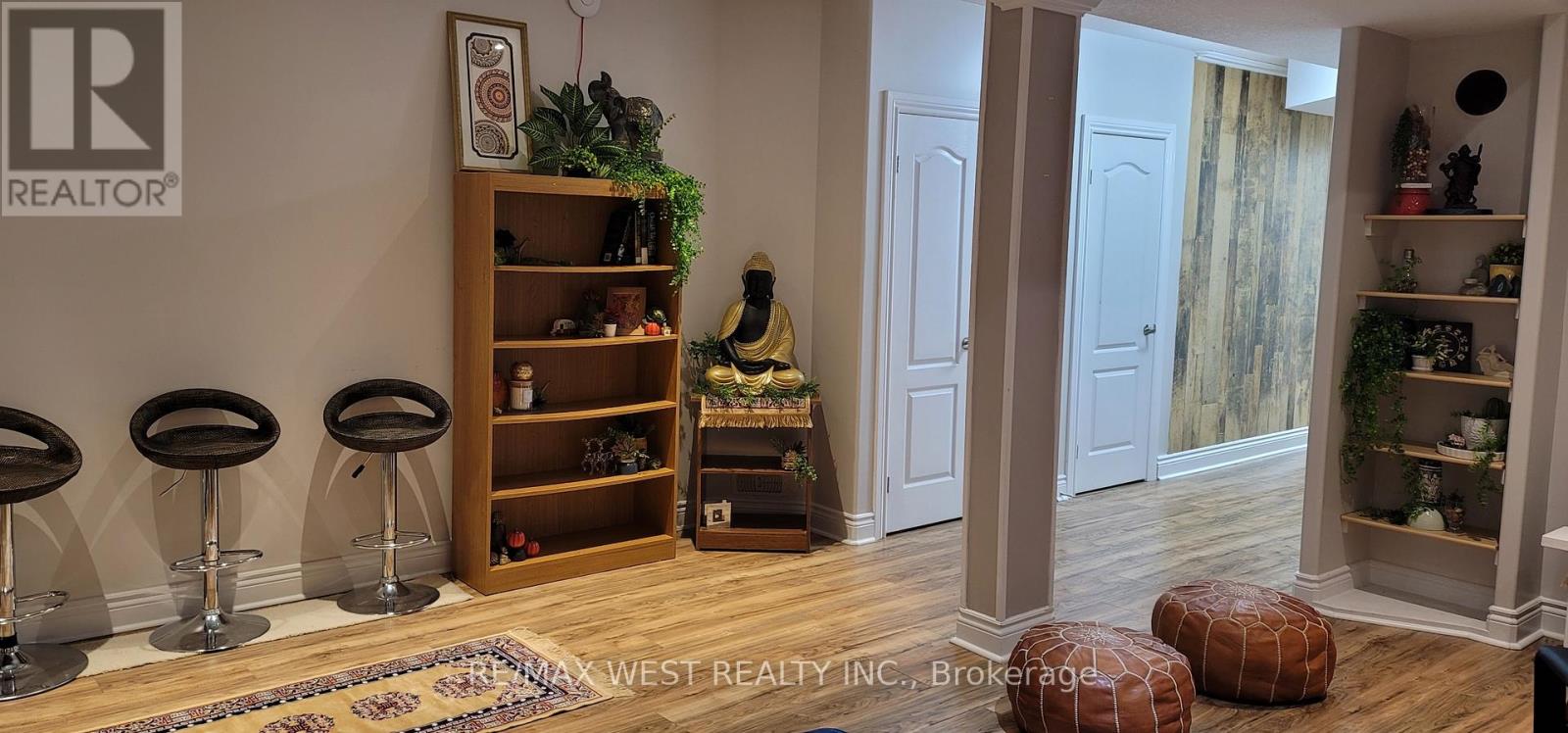 A room with a wooden floor and a white wall with a REALTOR sign on it.