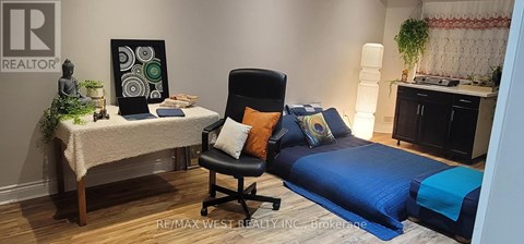 A bedroom with a bed, chair, and a small table with a plant on it.