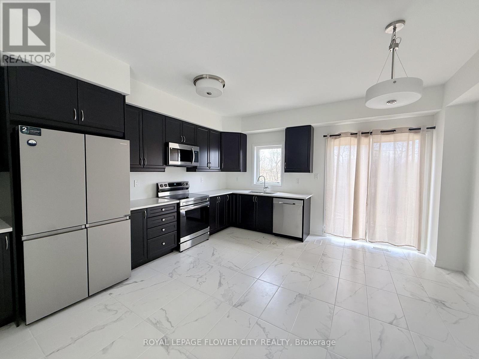 A spacious kitchen with black cabinets and a white refrigerator.
