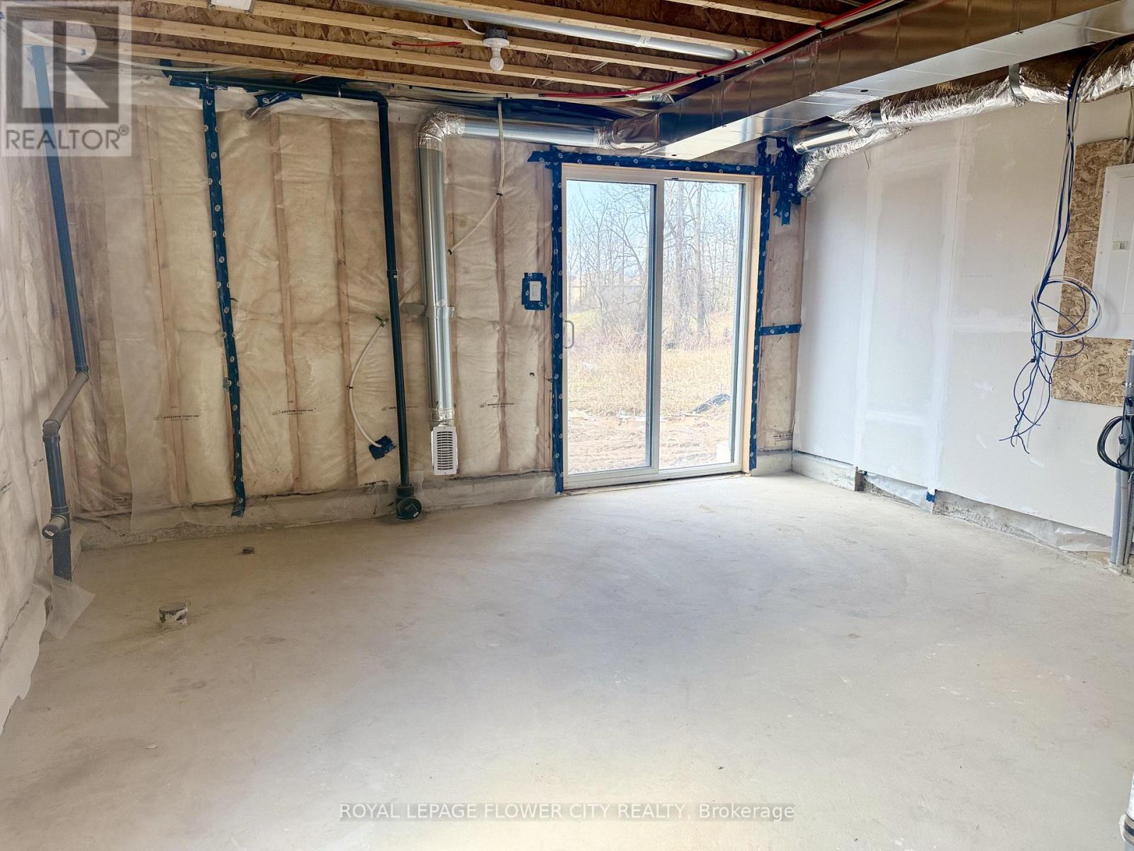 A room under construction with exposed pipes and drywall.
