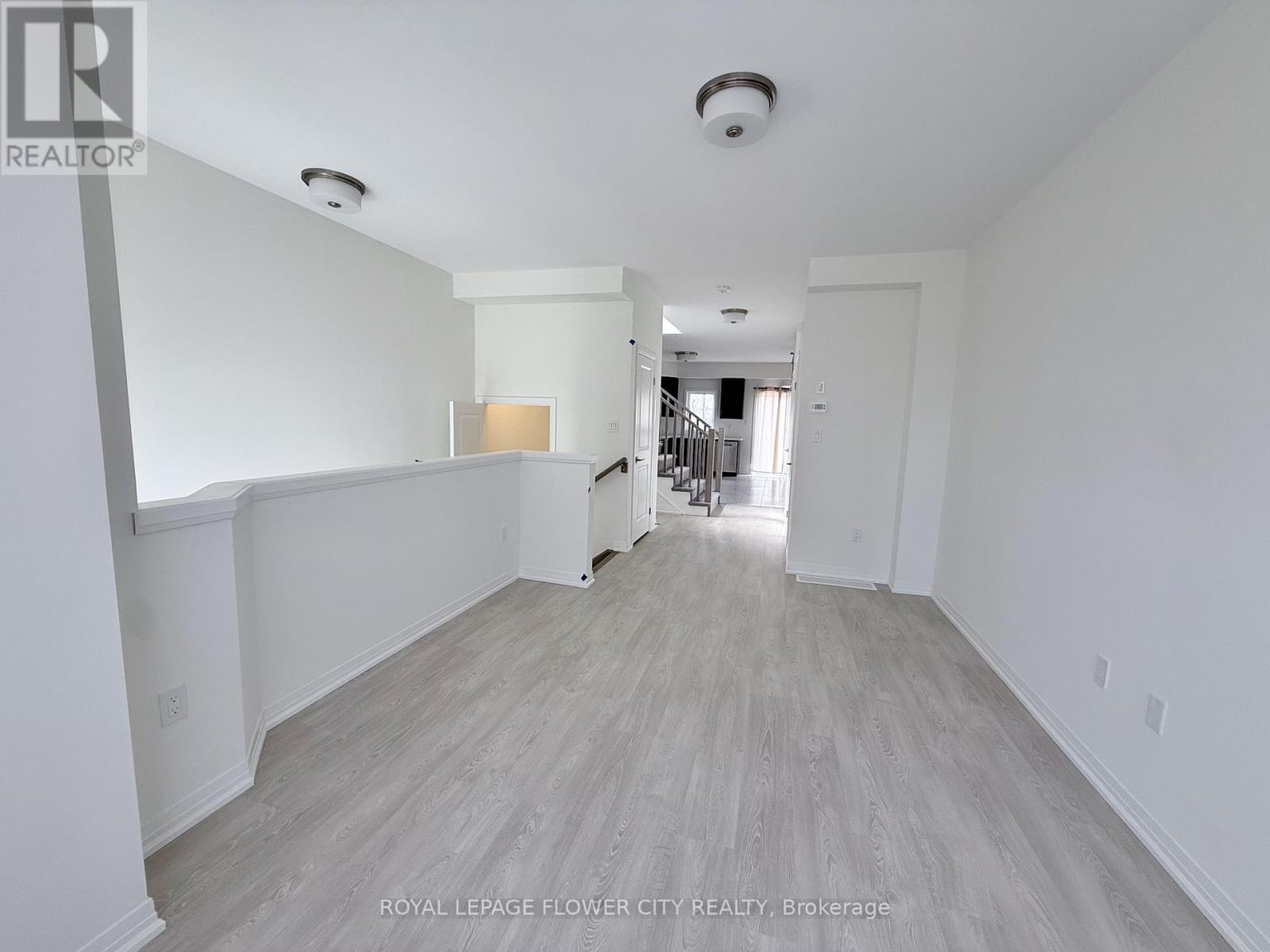 A spacious room with white walls and wood flooring.