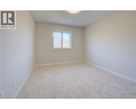 A white bedroom with a window and carpeted floor.