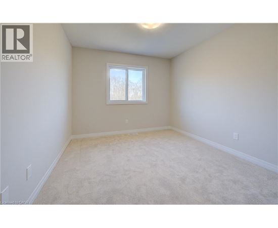 A white bedroom with a window and carpeted floor.