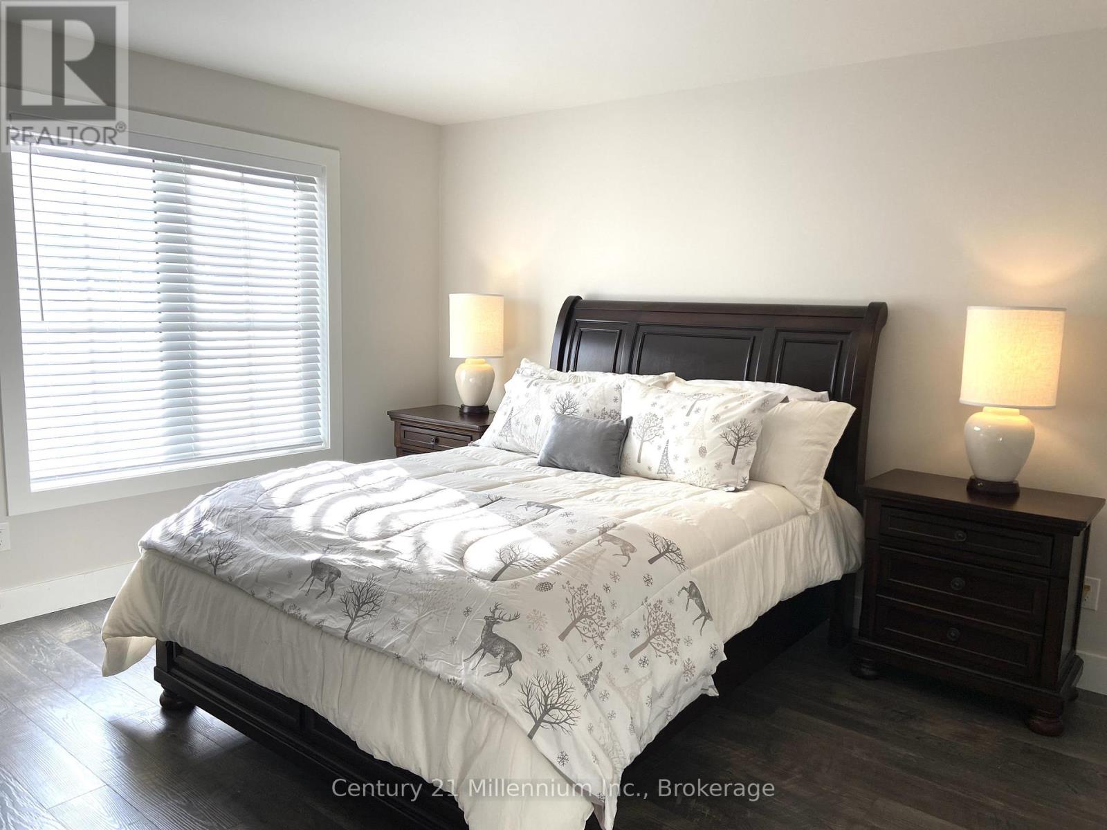 A bedroom with a large bed and two lamps.