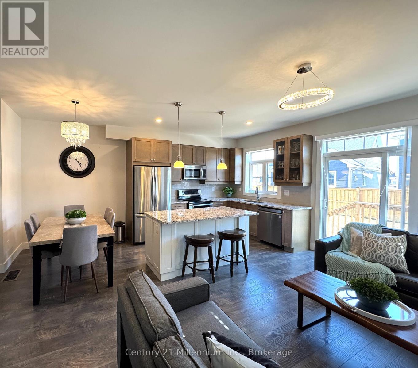 A well-lit open plan living and kitchen area with a dining table and bar stools.