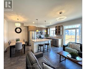 A well-lit open plan living and kitchen area with a dining table and bar stools.