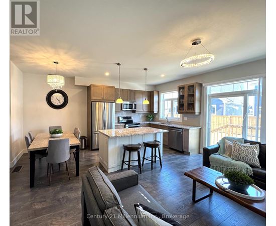 A well-lit open plan living and kitchen area with a dining table and bar stools.