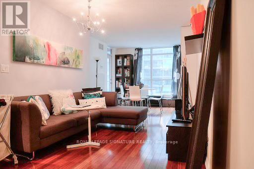 A living room with a brown couch and a painting on the wall.