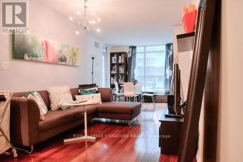 A living room with a brown couch and a painting on the wall.