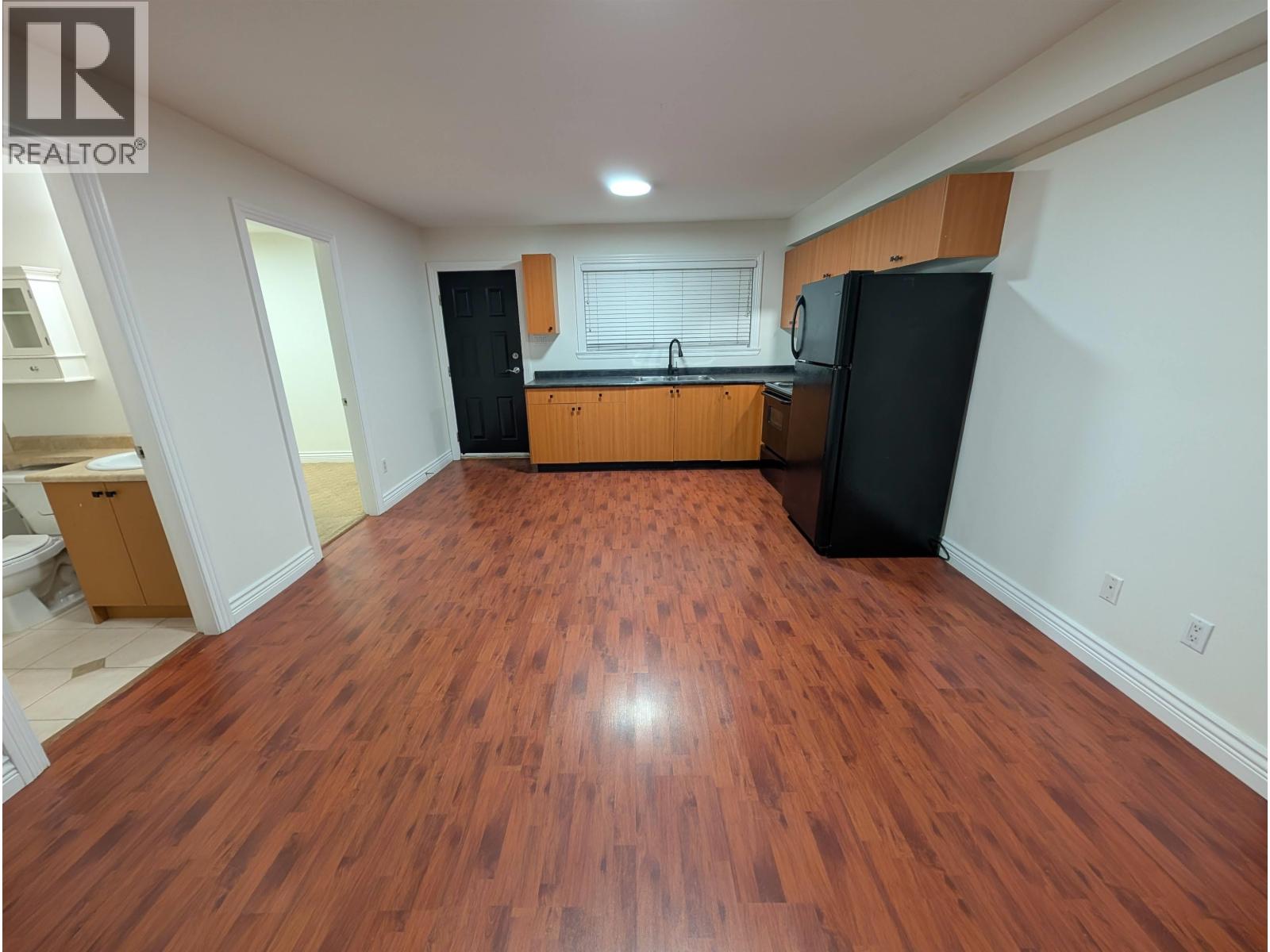 A kitchen with wooden floors and black appliances.