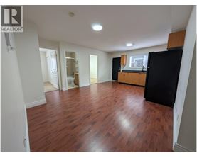 A room with wooden floors and a black refrigerator.