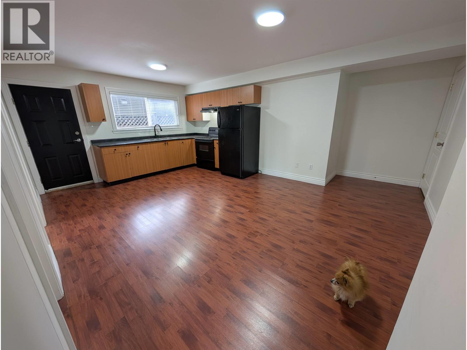 A kitchen with wooden floors and black appliances.