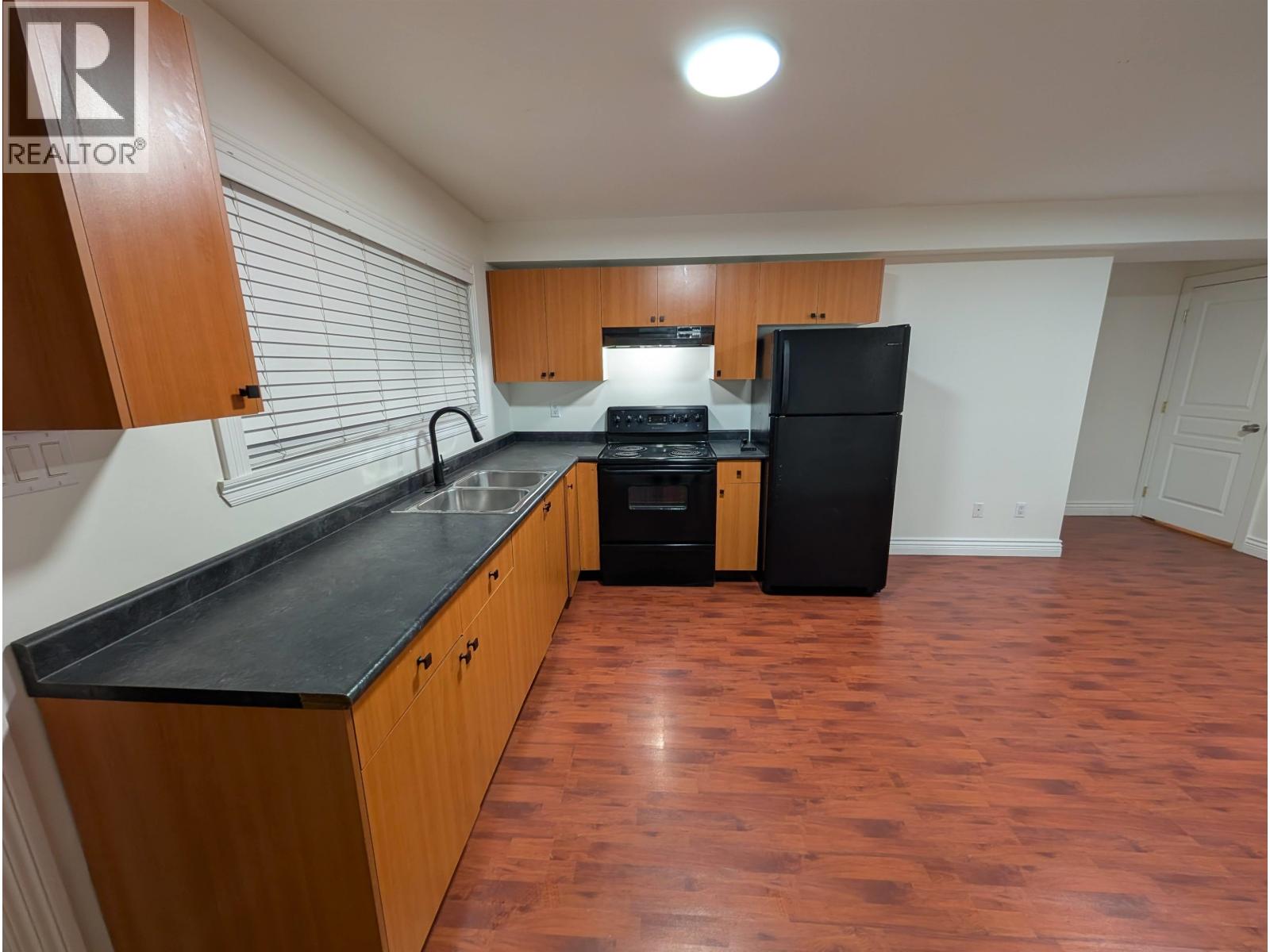 A kitchen with wooden cabinets and black countertops.