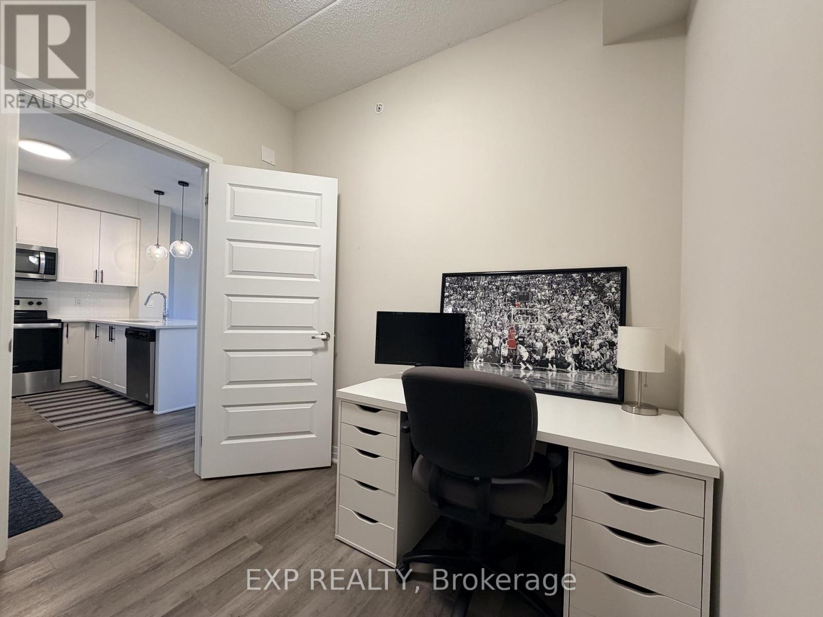 A white office space with a desk, chair, and a television on the wall.