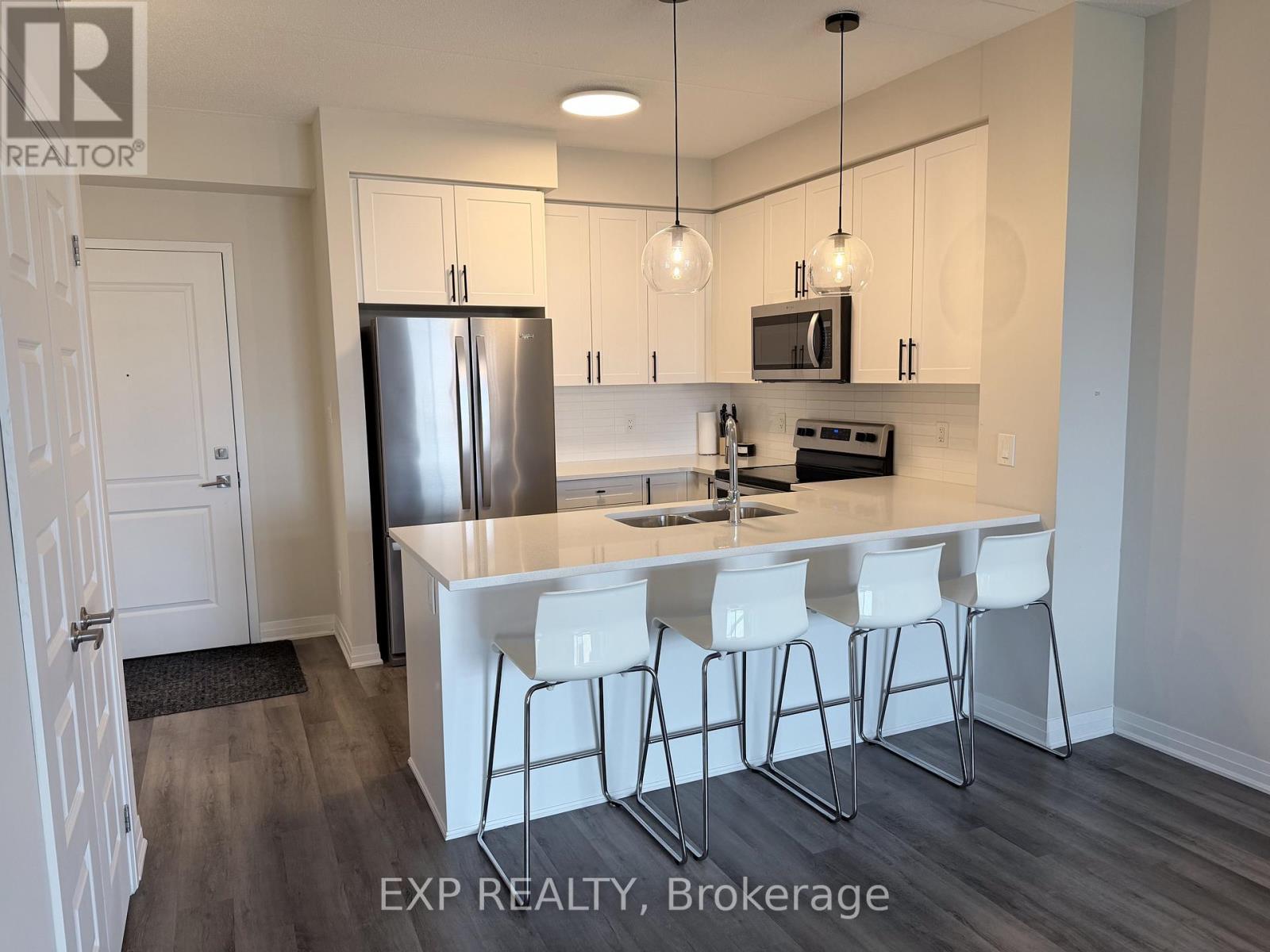 A kitchen with white chairs and a white island.