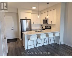 A kitchen with white chairs and a white island.