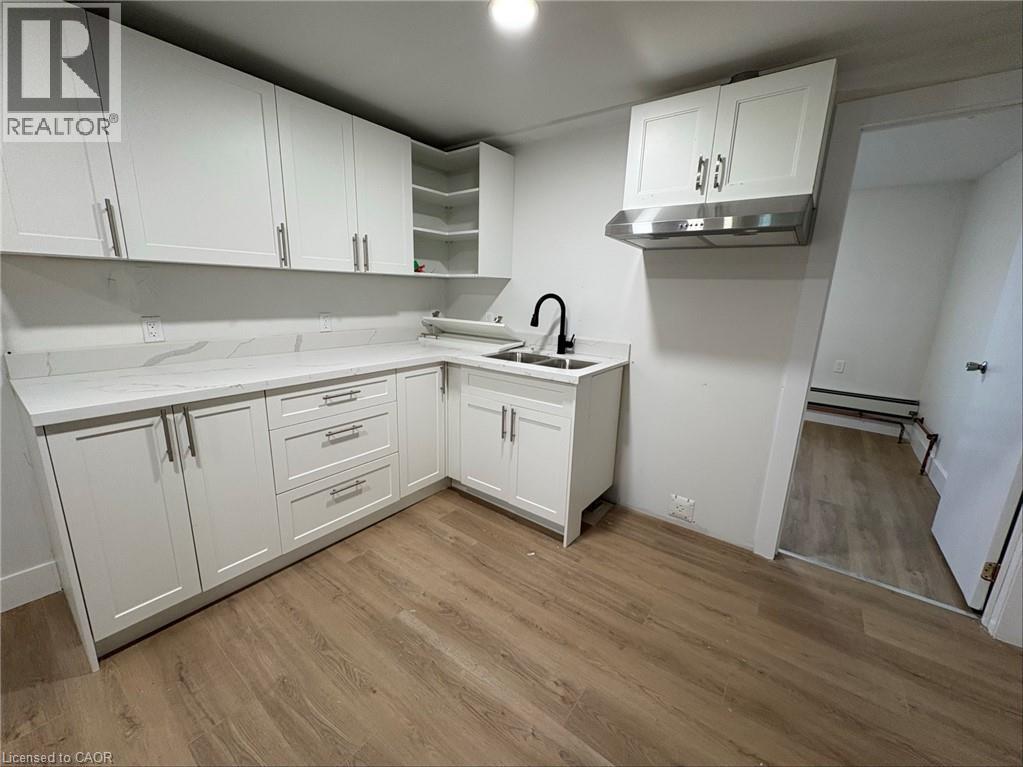 A kitchen with white cabinets and a wooden floor.