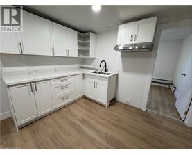A kitchen with white cabinets and a wooden floor.