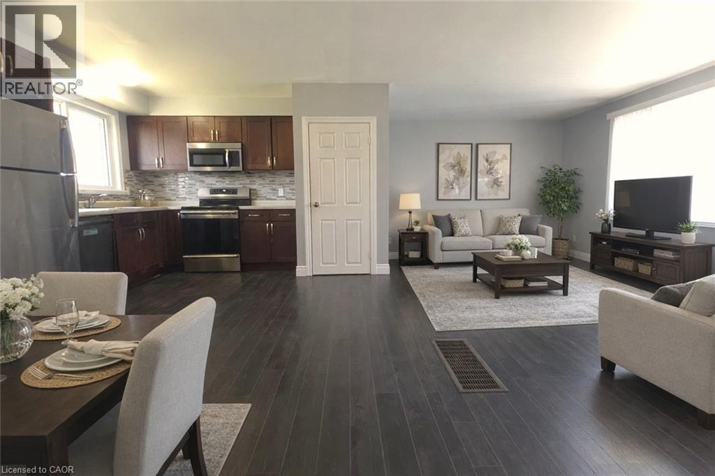A well-lit, modern kitchen and living room with dark wood floors and furnished with a dining table and chairs.