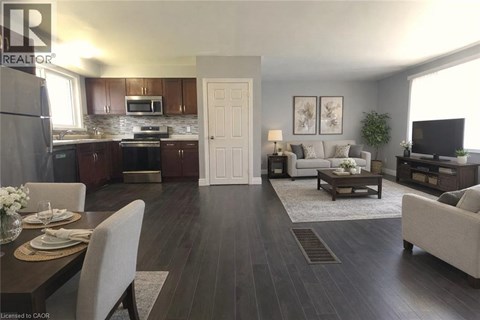 A well-lit, modern kitchen and living room with dark wood floors and furnished with a dining table and chairs.