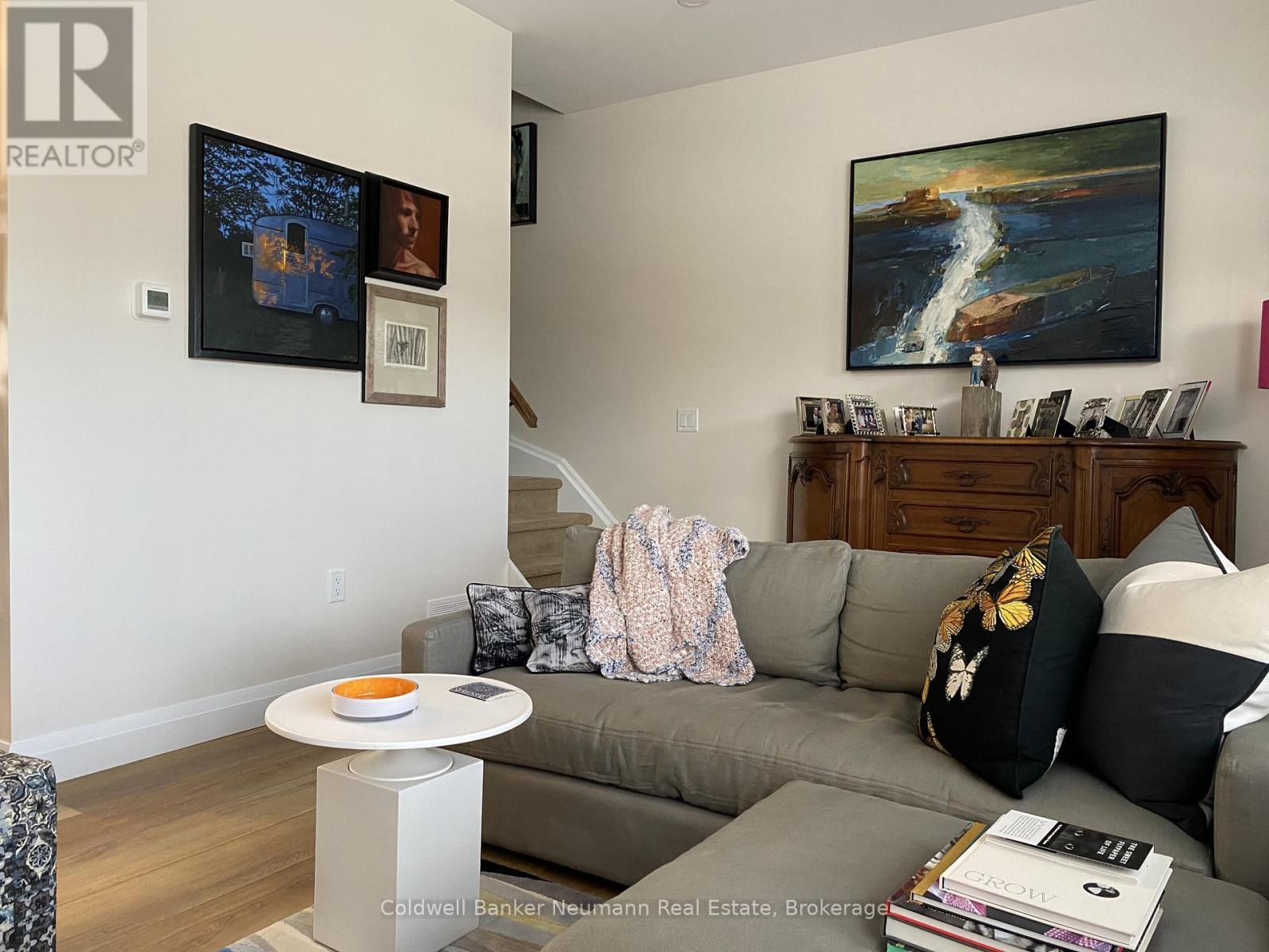 A living room with a grey couch and a painting on the wall.