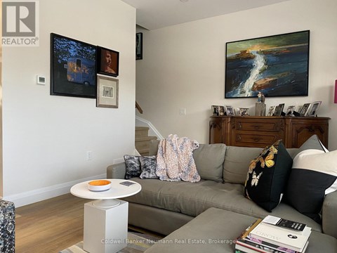 A living room with a grey couch and a painting on the wall.