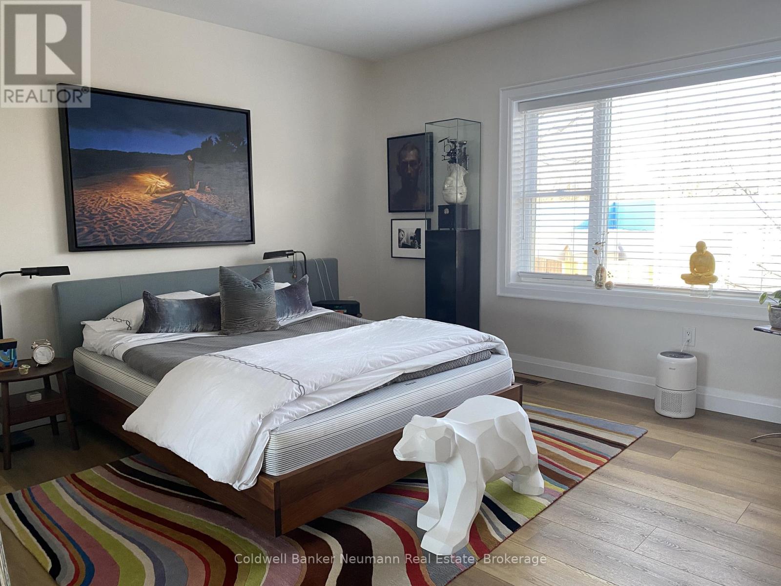 A bedroom with a large bed and a painting on the wall.
