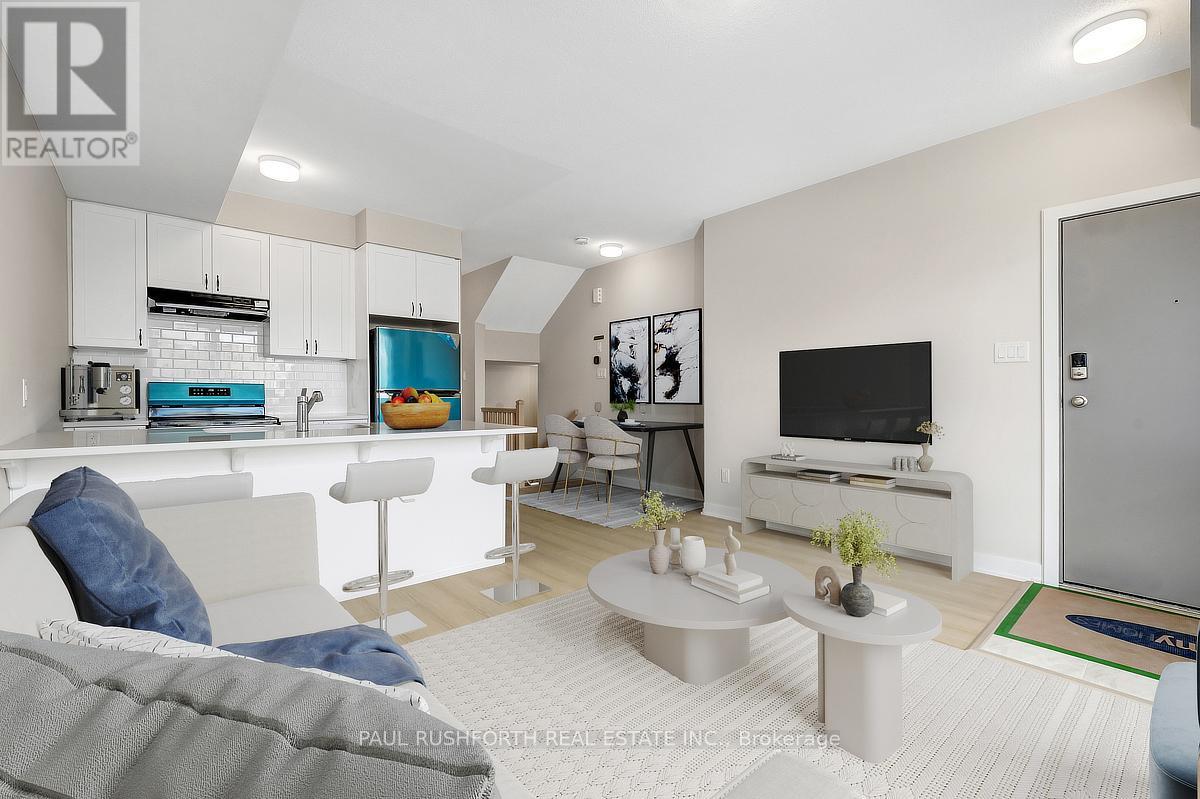 A modern living room with a grey couch and a white kitchen area.