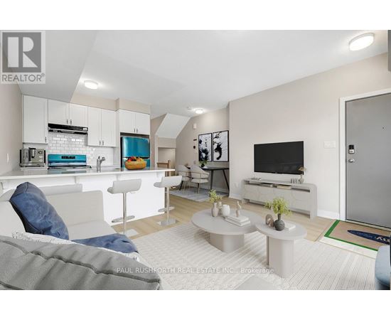 A modern living room with a grey couch and a white kitchen area.