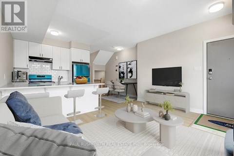A modern living room with a grey couch and a white kitchen area.