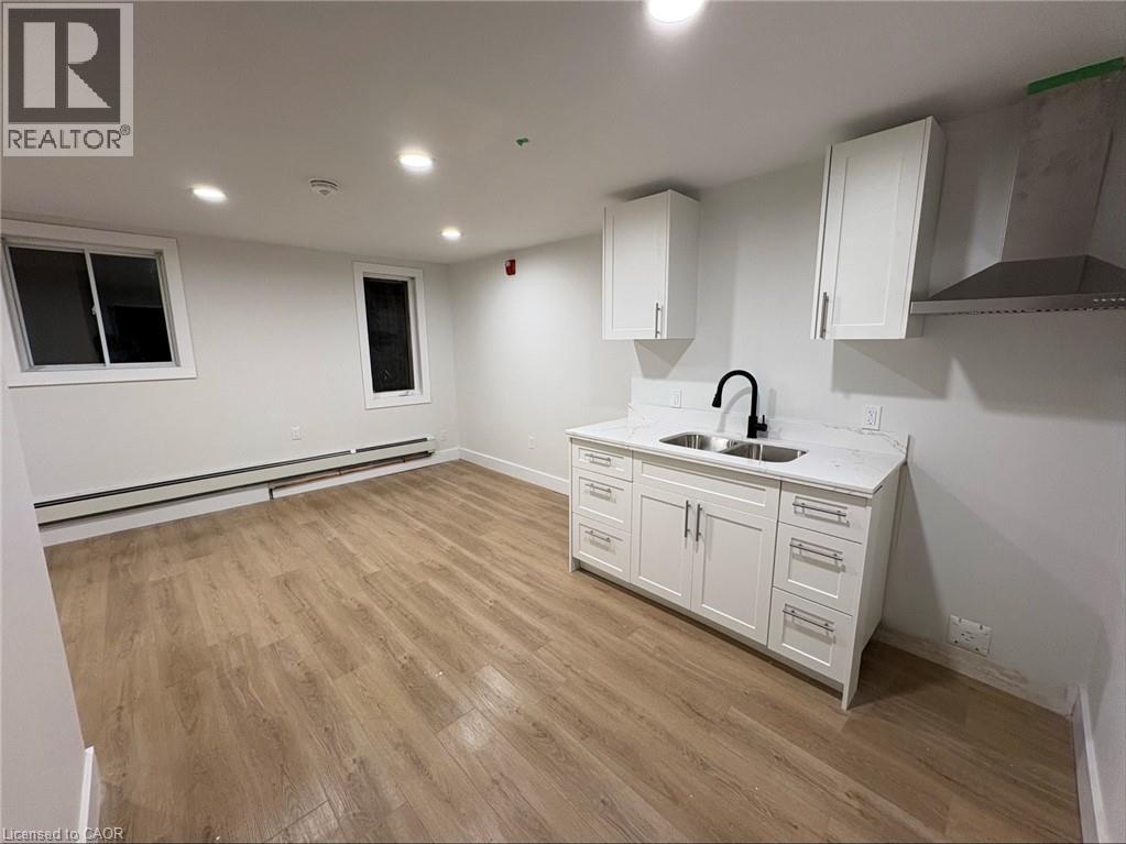 A kitchen with white cabinets and a wooden floor.