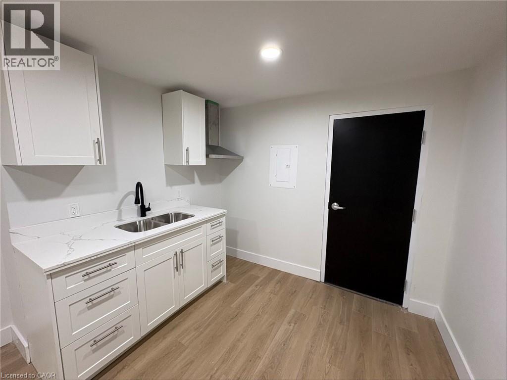 A kitchen with white cabinets and a black door.
