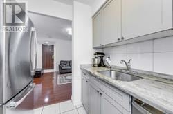 A kitchen with a stainless steel refrigerator and a marble countertop.